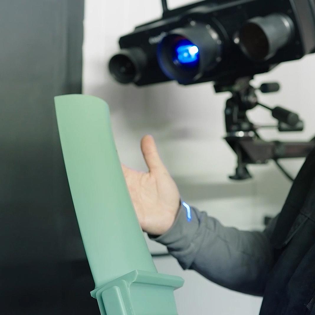 An inspector examining a wax model of a blade, focusing on its shapes to ensure accuracy and precision in design.