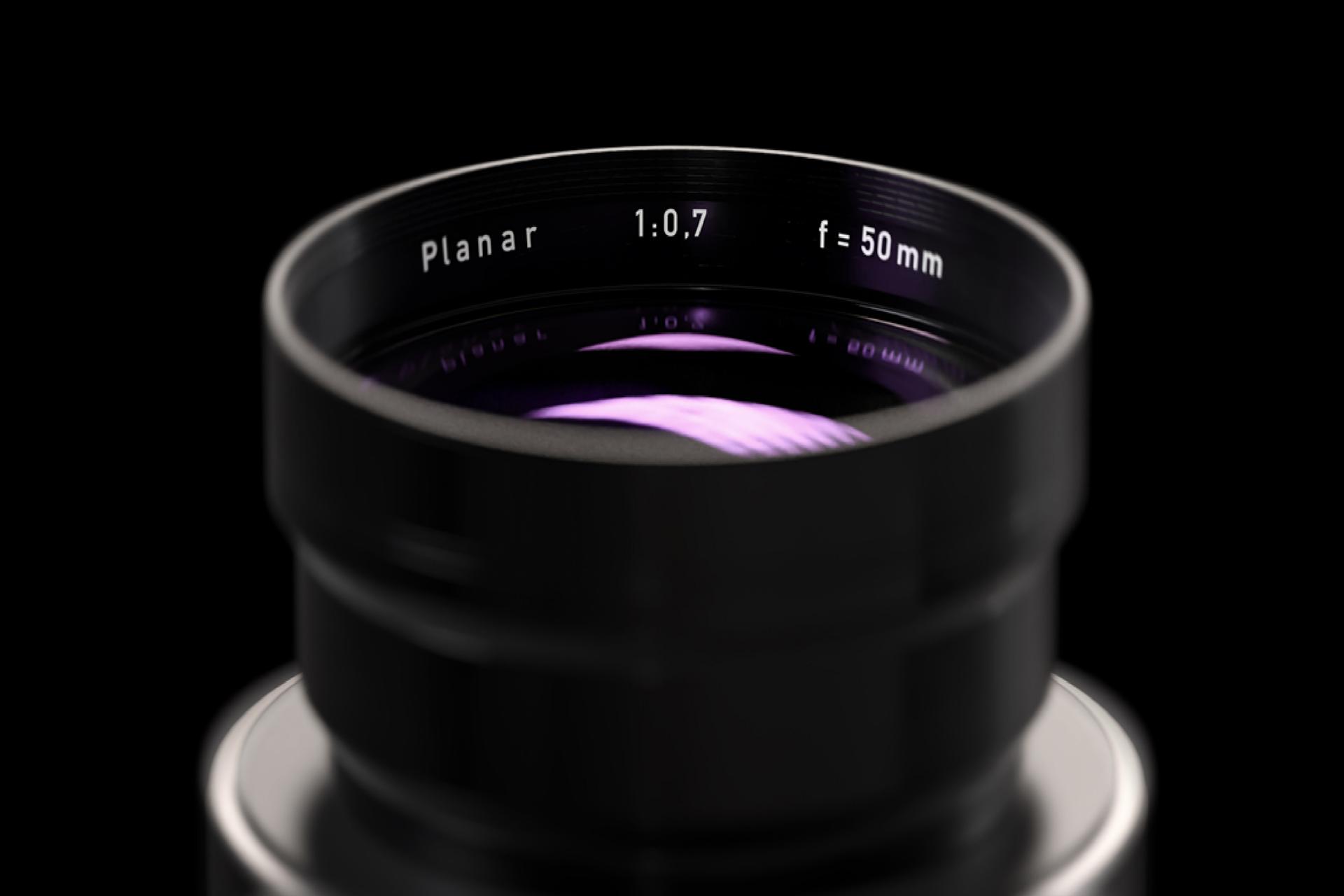 Close-up view of a ZEISS Planar 50mm f/0.7 camera lens with visible glass reflections and engraved specifications.