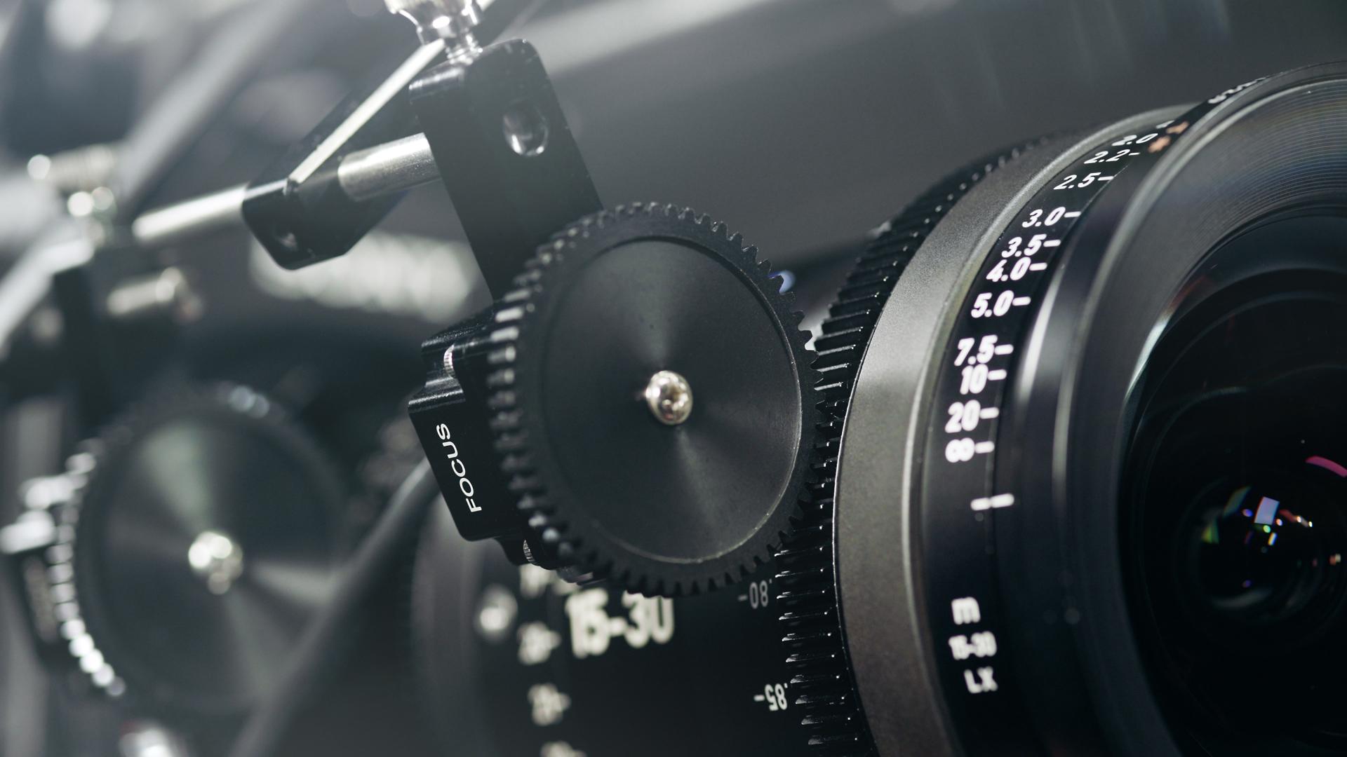 Close-up of a professional cinema camera lens with focus and zoom control rings, showcasing ZEISS branding and precision engineering.