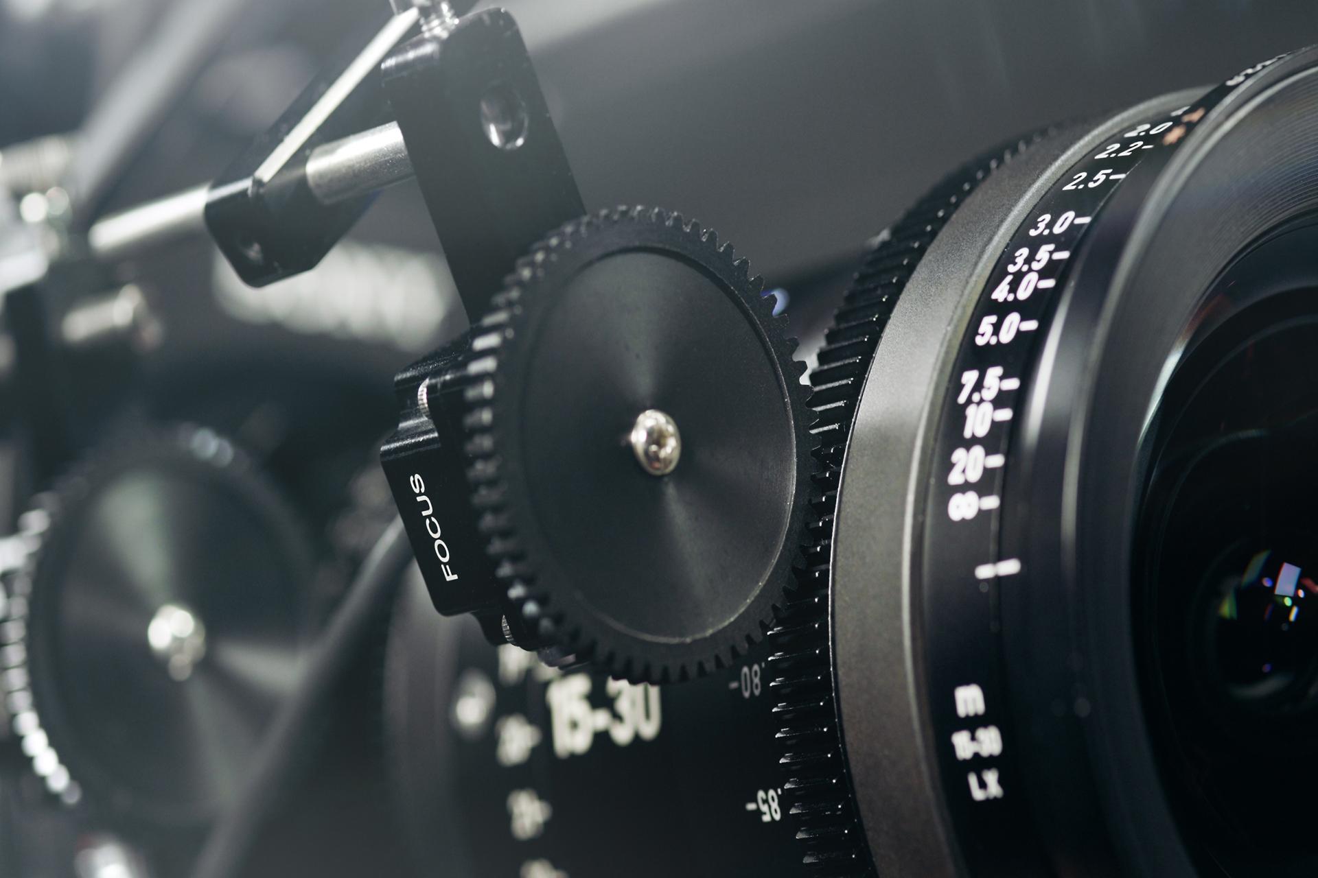 Close-up of a professional cinema camera lens with focus and zoom control rings, showcasing ZEISS branding and precision engineering.