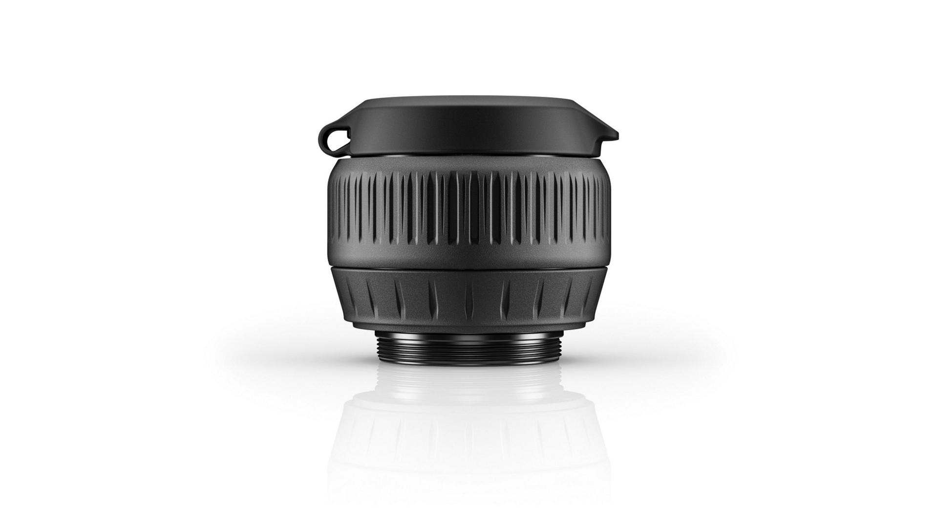 Black ZEISS camera lens viewed from the front with a protective cap and ribbed grip design, displayed on a white reflective surface.