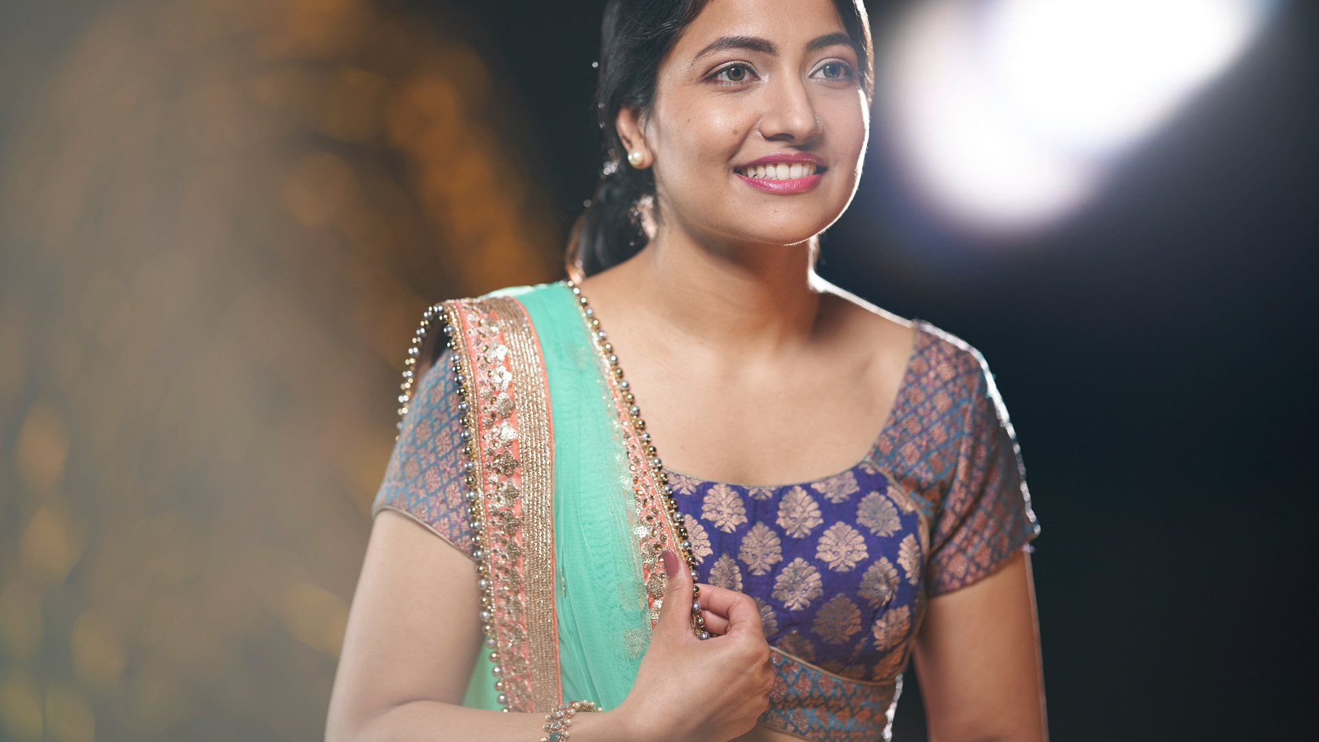 A woman in traditional attire standing gracefully in an artistically lit set, captured with the clarity and precision of ZEISS optics.