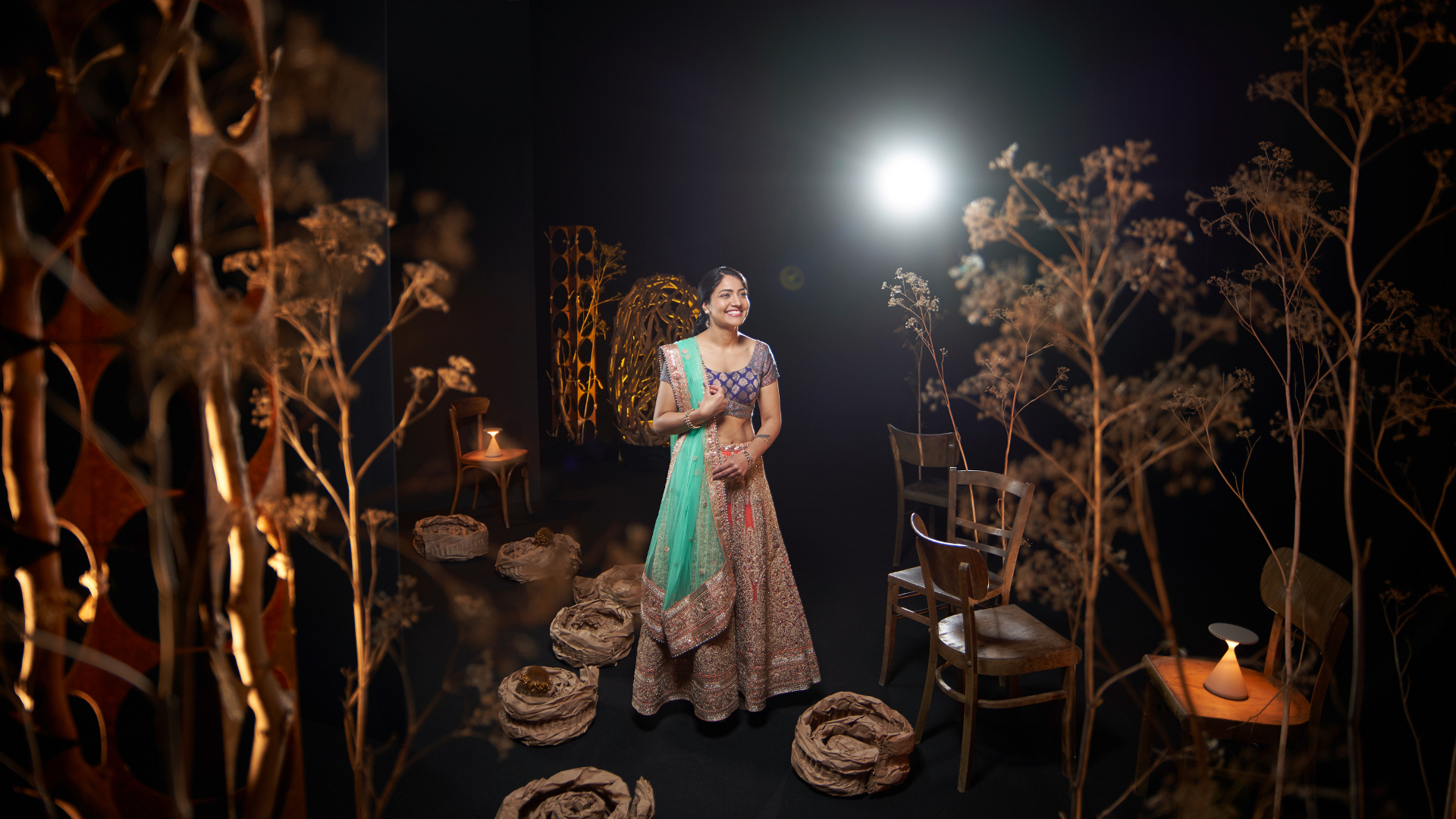 A woman in traditional attire standing gracefully in an artistically lit set, captured with the clarity and precision of ZEISS optics.