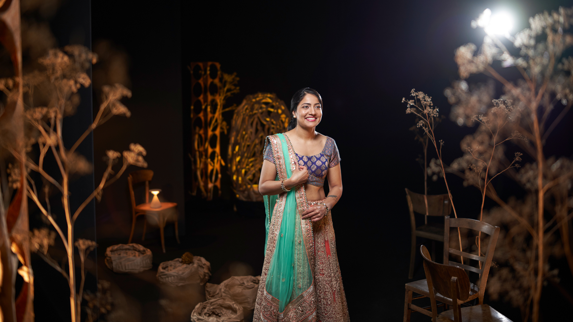 A woman in traditional attire standing gracefully in an artistically lit set, captured with the clarity and precision of ZEISS optics.