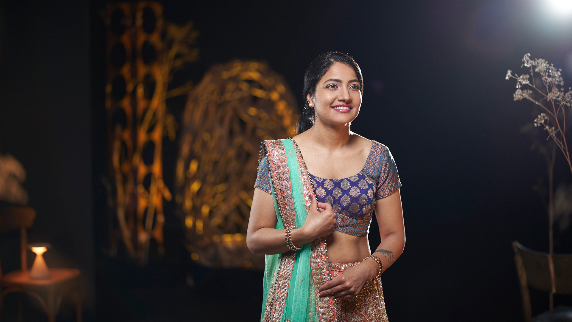 A woman in traditional attire standing gracefully in an artistically lit set, captured with the clarity and precision of ZEISS optics.