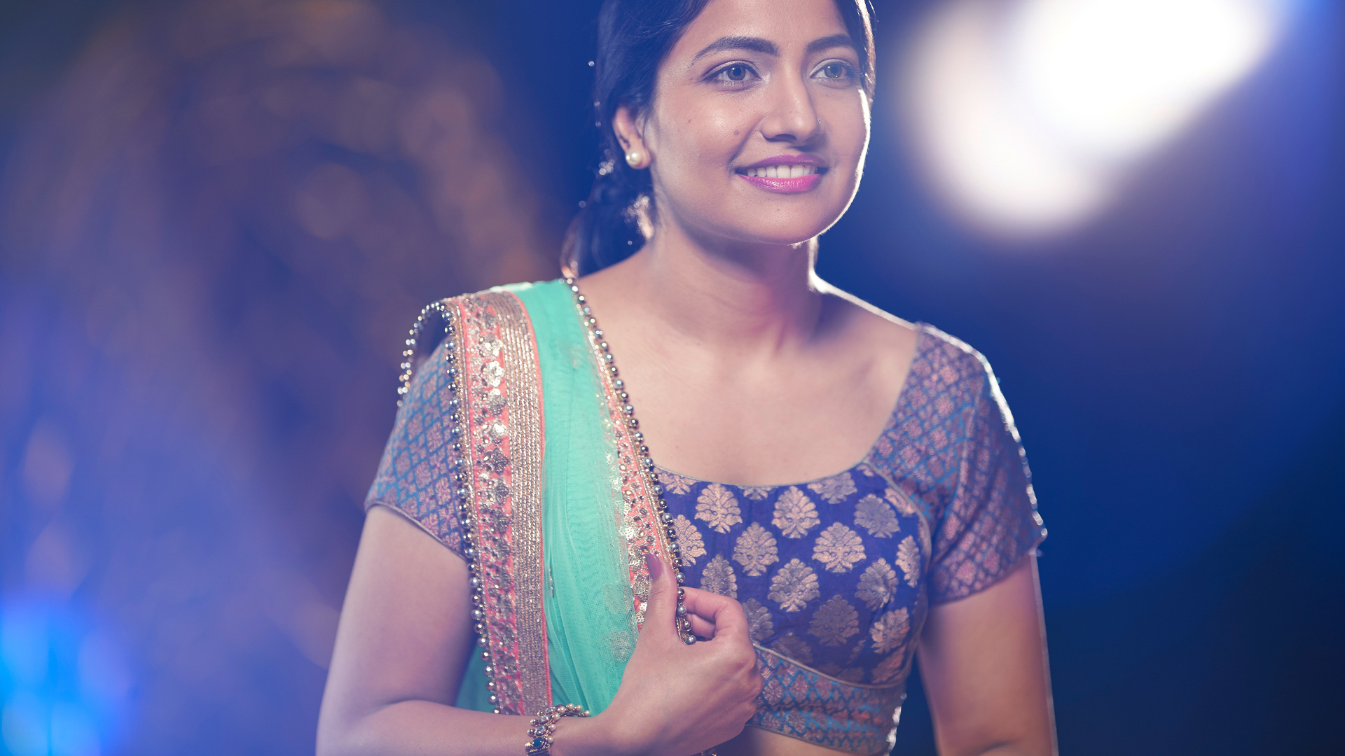 A woman in traditional attire standing gracefully in an artistically lit set, captured with the clarity and precision of ZEISS optics.