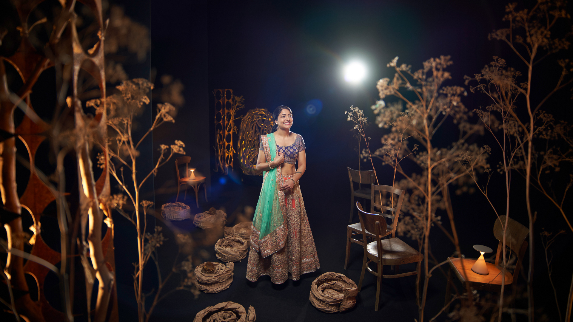A woman in traditional attire standing gracefully in an artistically lit set, captured with the clarity and precision of ZEISS optics.