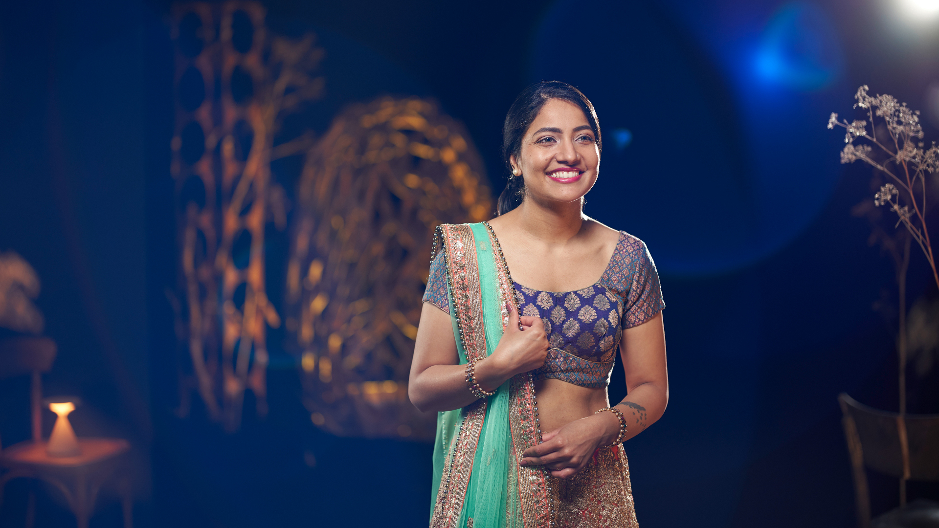 A woman in traditional attire standing gracefully in an artistically lit set, captured with the clarity and precision of ZEISS optics.