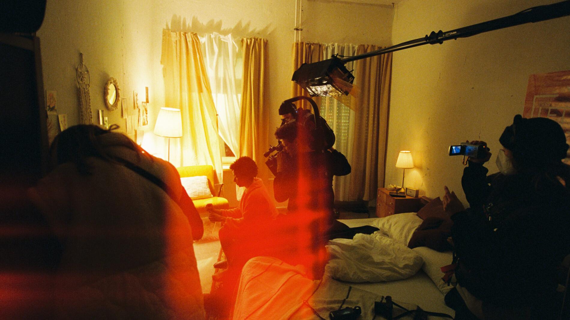 A film crew captures a scene in a dimly lit bedroom with ZEISS camera equipment visible.
