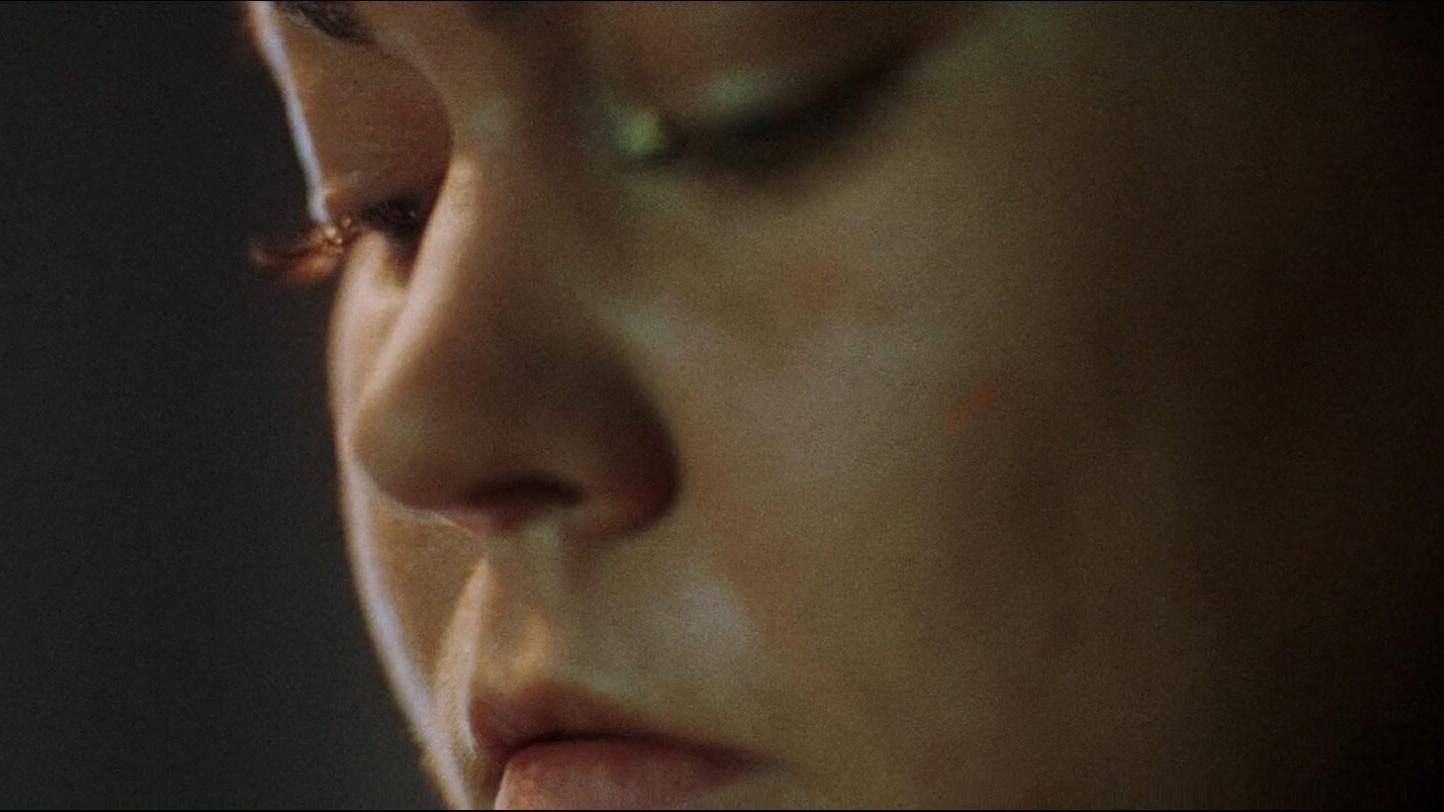 Close-up of a person's face in soft focus with detailed lighting and shallow depth of field.
