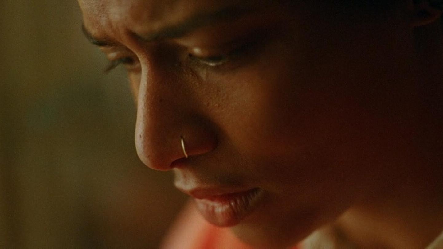 Close-up of a person's face in soft, warm lighting, showcasing detailed focus and emotional expression, captured with ZEISS lens quality.