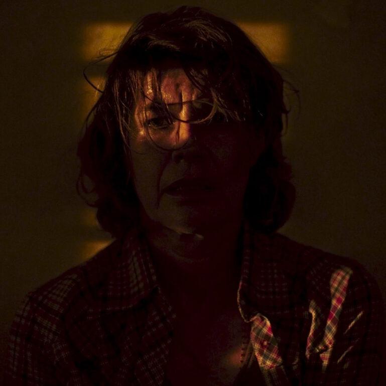 A group of people stands outdoors while a teenage boy reads from a paper as reporters hold microphones toward him.