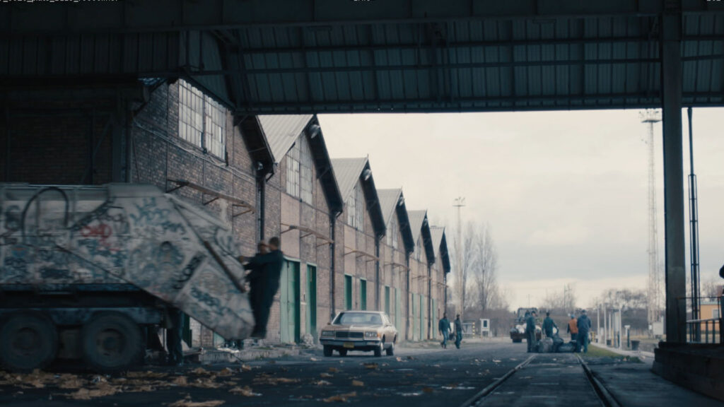 Two people are working with professional film production equipment, including a camera and monitor, in a studio setting featuring ZEISS lenses.