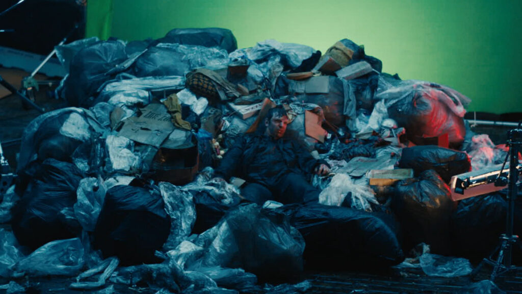 A group of people stands outdoors while a teenage boy reads from a paper as reporters hold microphones toward him.