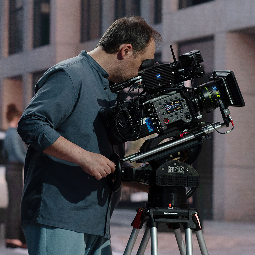 A cameraman operating a professional film camera equipped with ZEISS lenses and mounted on a stabilizer for high-precision shooting.