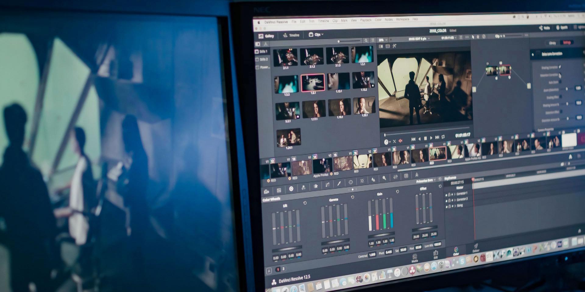 Dual monitors displaying a video editing software with various clips, timelines, and color grading tools visible in a professional post-production setup.