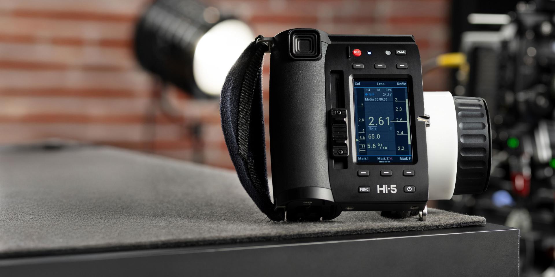 Professional ZEISS camera control unit with a digital display and ergonomic grip placed on a dark surface in a studio setting.