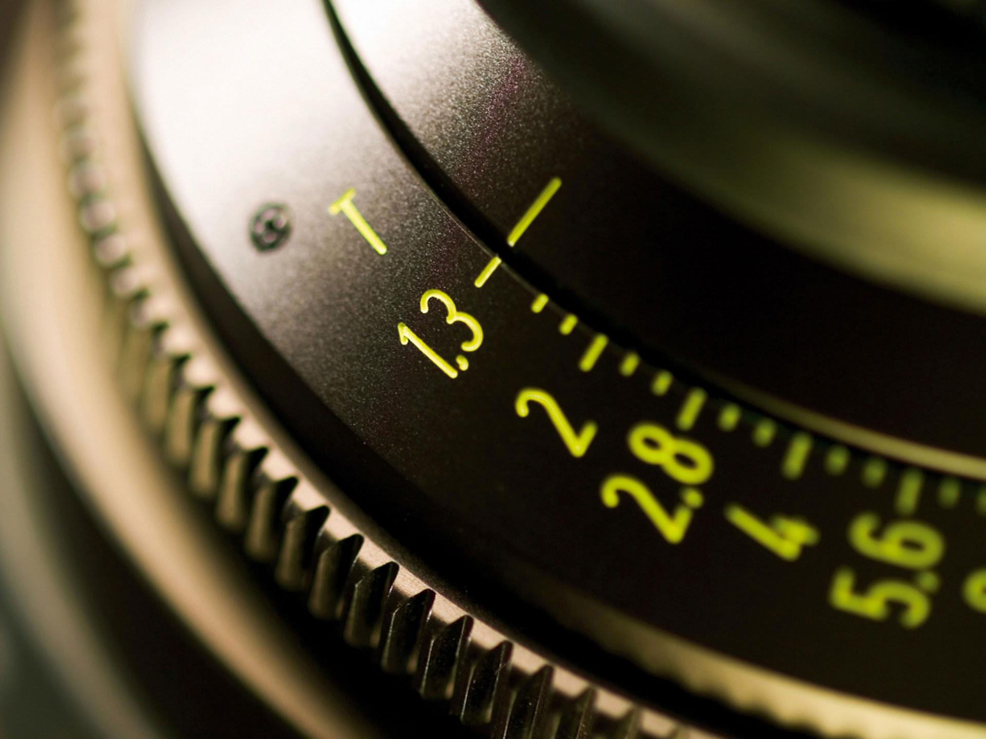Close-up image of a ZEISS camera lens showing detailed aperture and focus markings in yellow.