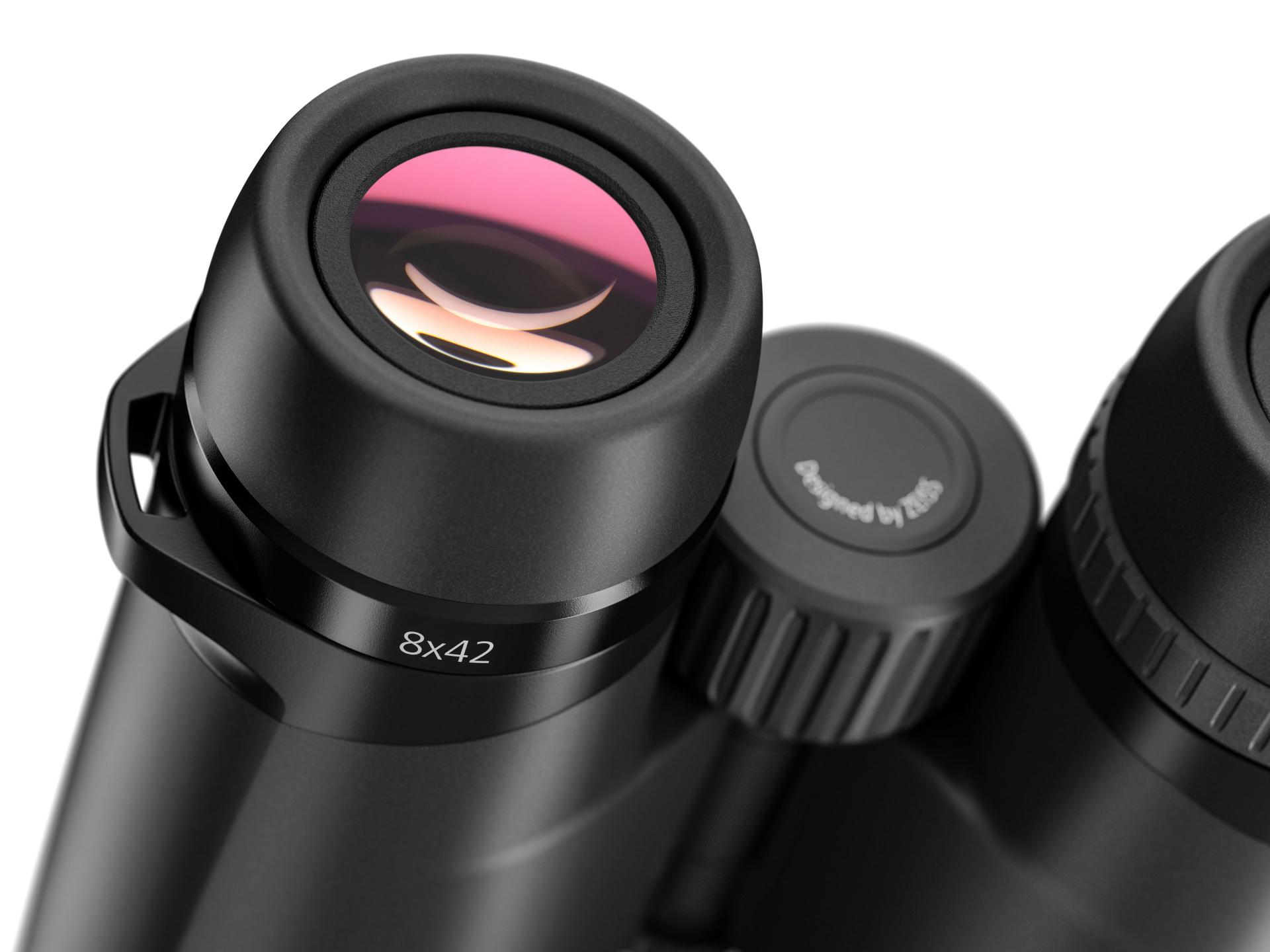 Close-up view of a pair of black ZEISS 8x42 binoculars showing the eyepiece, focus knob, and lens with purple coating.