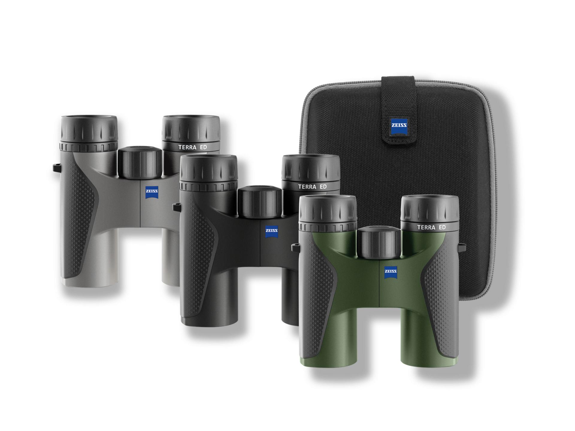 Three pairs of ZEISS Terra ED binoculars in black, gray, and green colors are displayed in front of a black ZEISS carrying case.