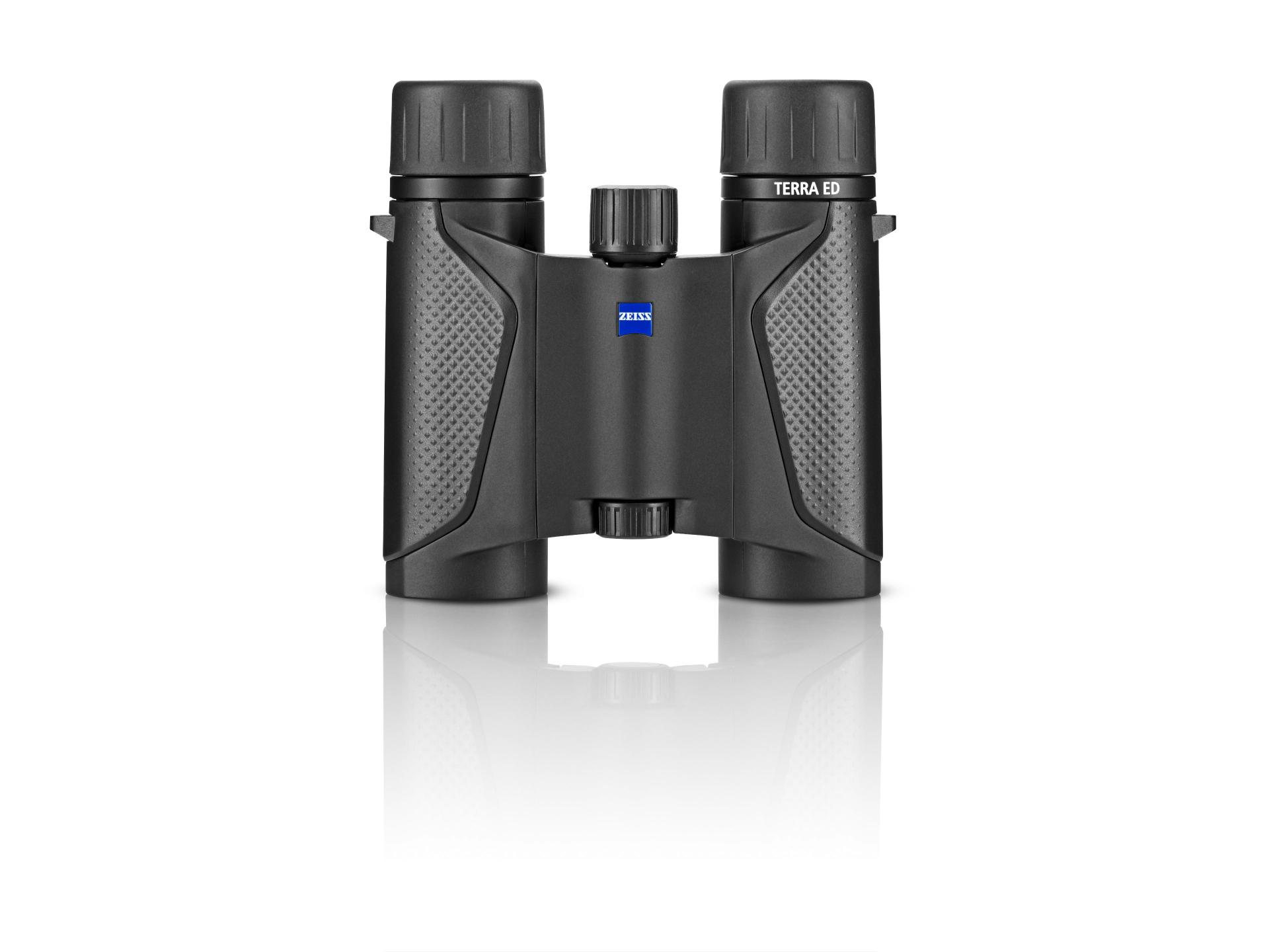 Black ZEISS TERRA ED binoculars with textured grips and a central focusing wheel, displayed on a white reflective surface.