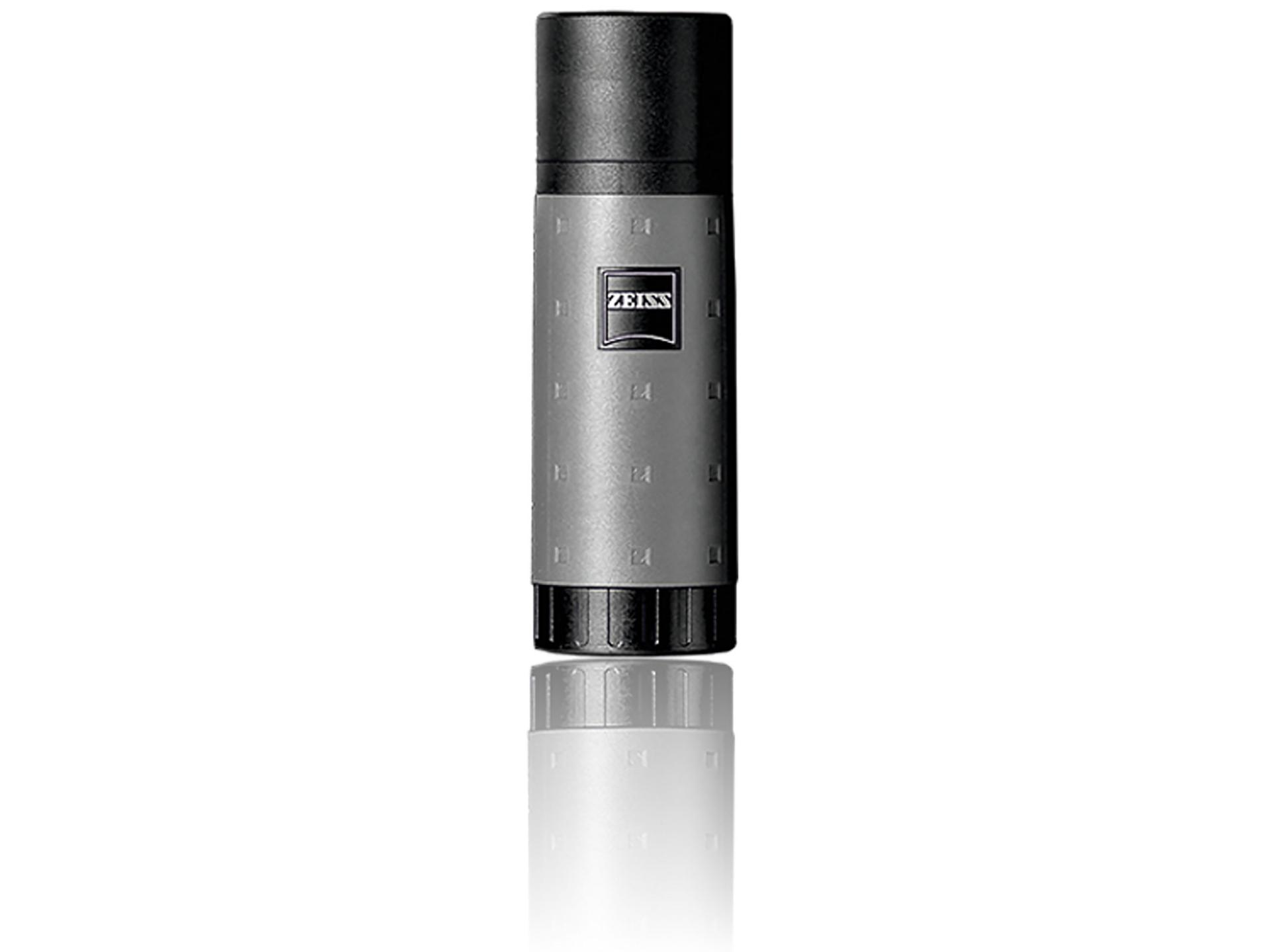 Grey and black cylindrical ZEISS lens cleaning spray bottle standing upright on a reflective white surface.