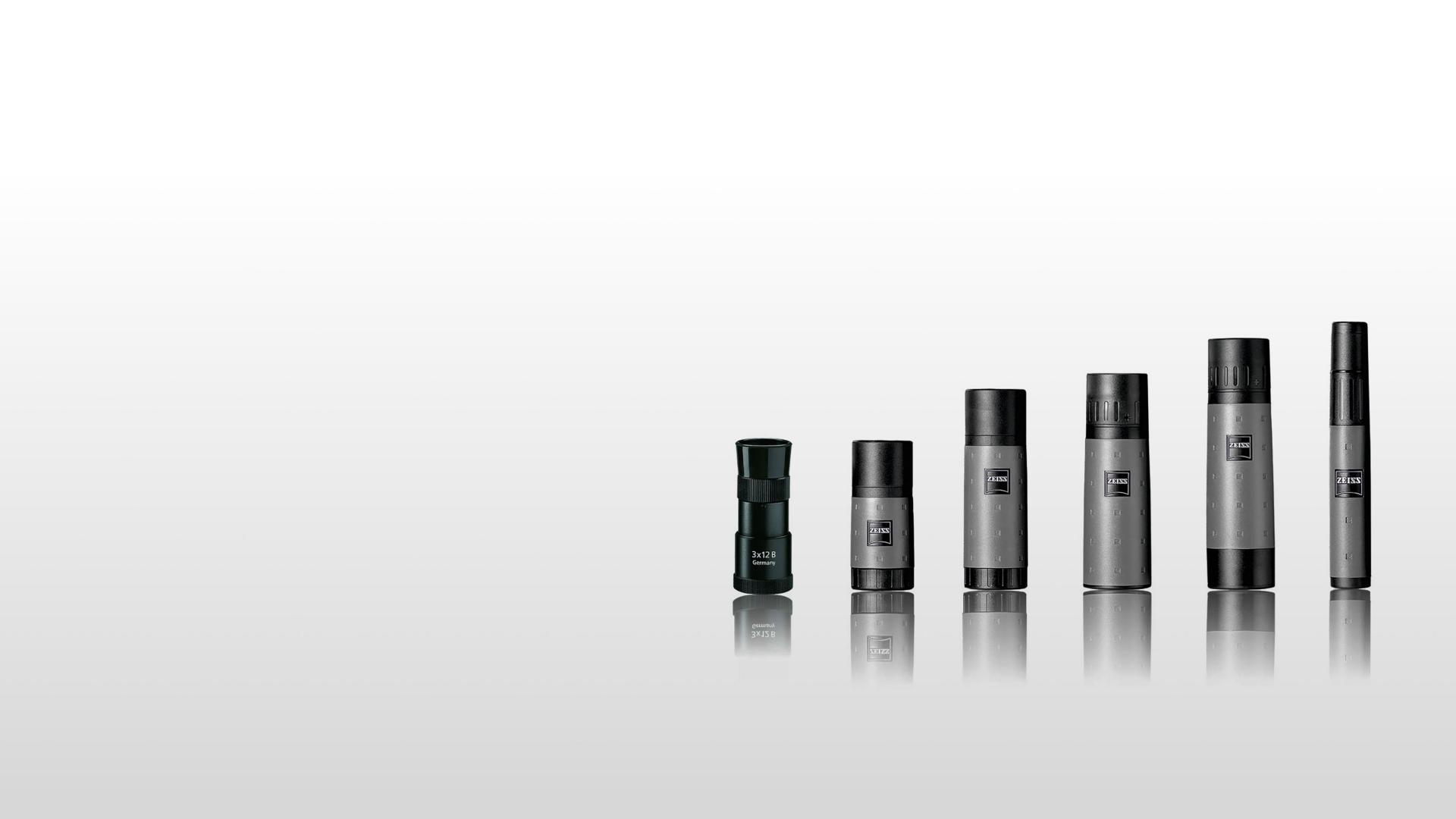 Six ZEISS monoculars of varying sizes are displayed in a row on a reflective surface against a gradient gray background.