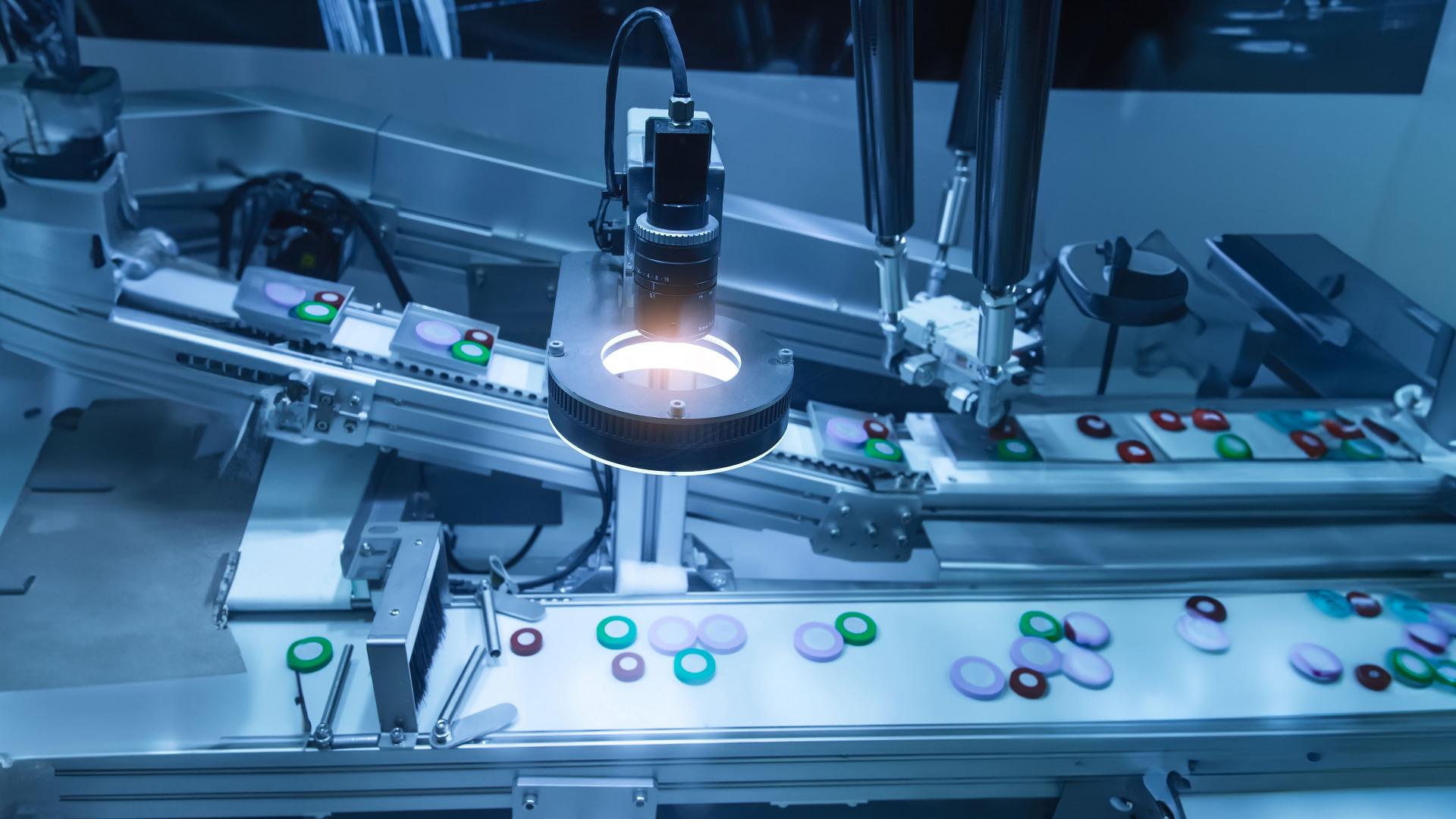 Automated inspection system analyzing colored plastic components on a conveyor belt under a precision optical sensor.