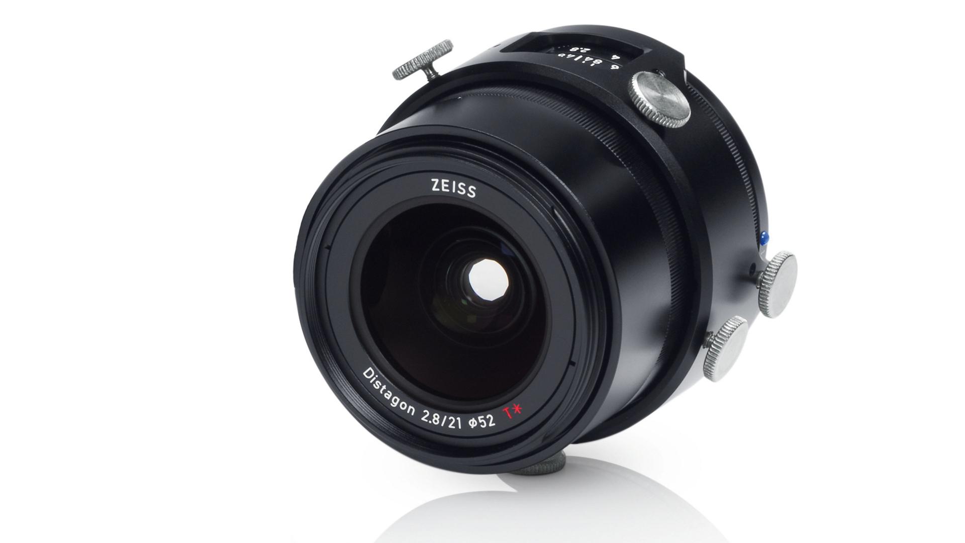 Close-up view of a ZEISS Distagon 2.8/21 camera lens with manual adjustment knobs on a white background.