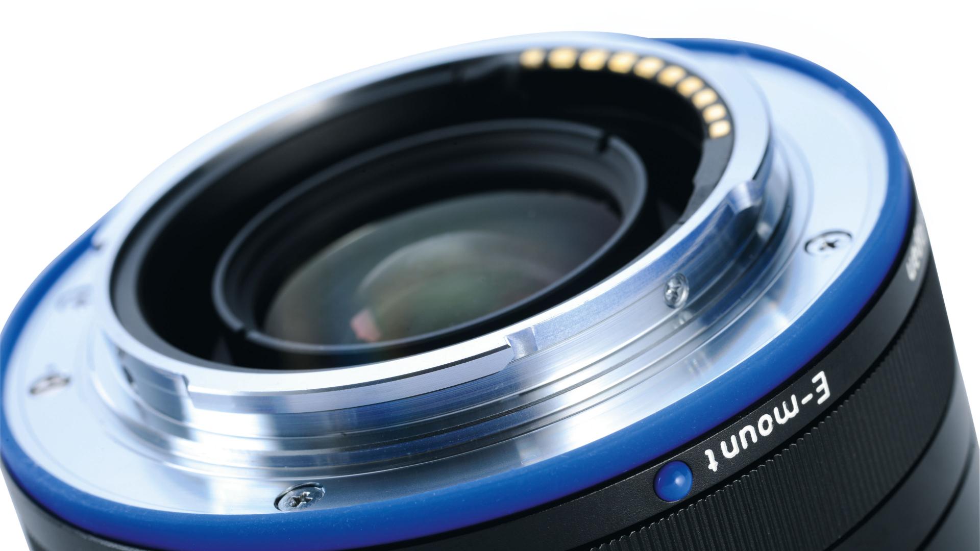 Close-up view of a ZEISS E-mount camera lens showing the metal mounting ring and electronic contact points.