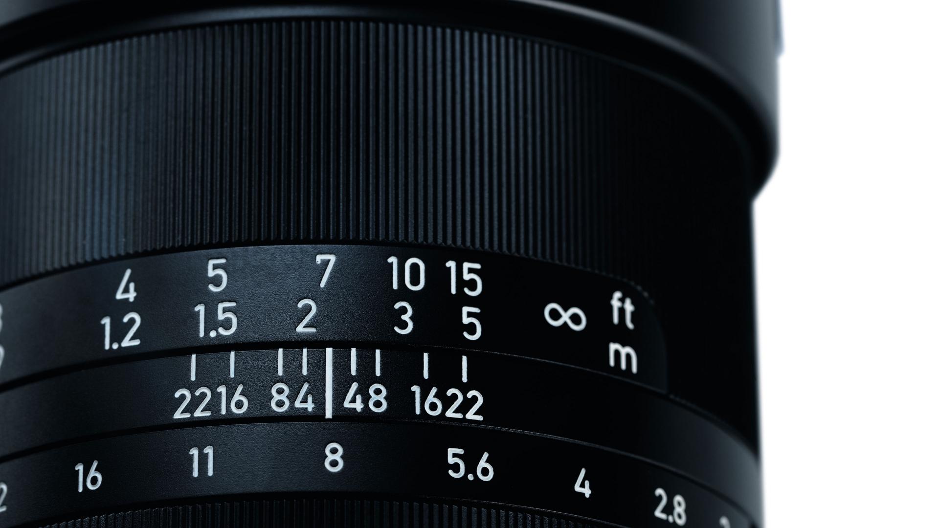 Close-up of a ZEISS camera lens showing focus distance and aperture settings.
