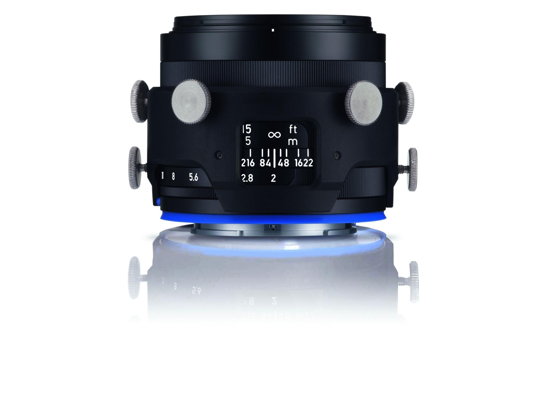 Professional camera lens with adjustment knobs and distance markings, displayed on a reflective surface.