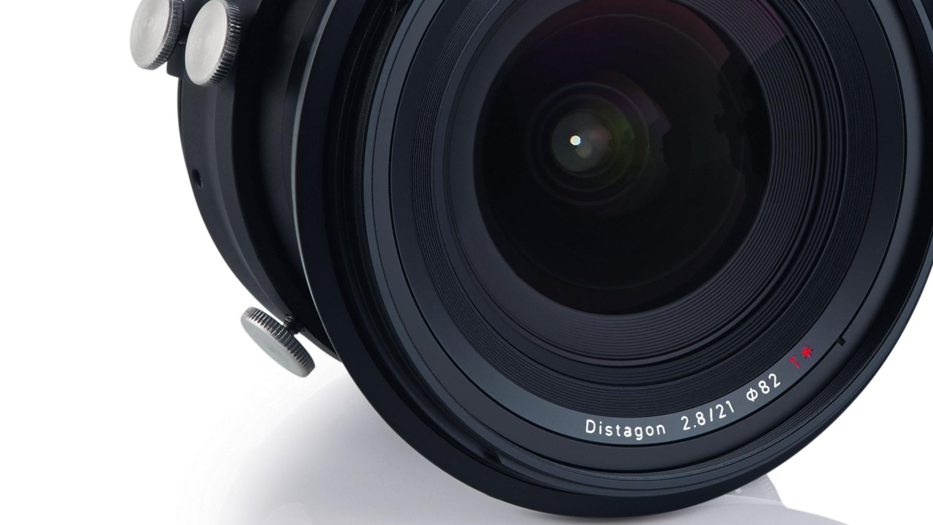 Close-up of a ZEISS Distagon 2.8/21 camera lens showing detailed front elements and control knobs.
