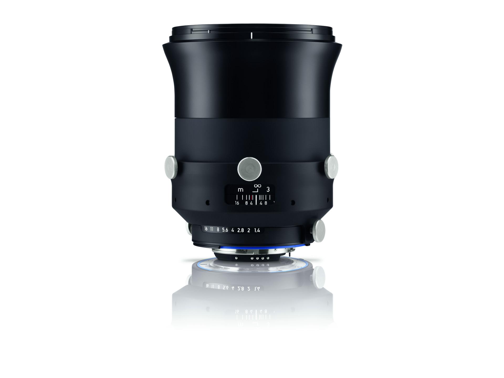 Black ZEISS camera lens with distance and aperture markings, displayed vertically on a white reflective surface.