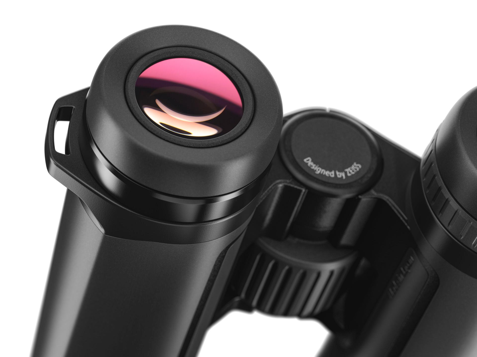 Close-up view of a black ZEISS binocular showing the eyepiece with a pink-tinted lens and the "Designed by ZEISS" label.
