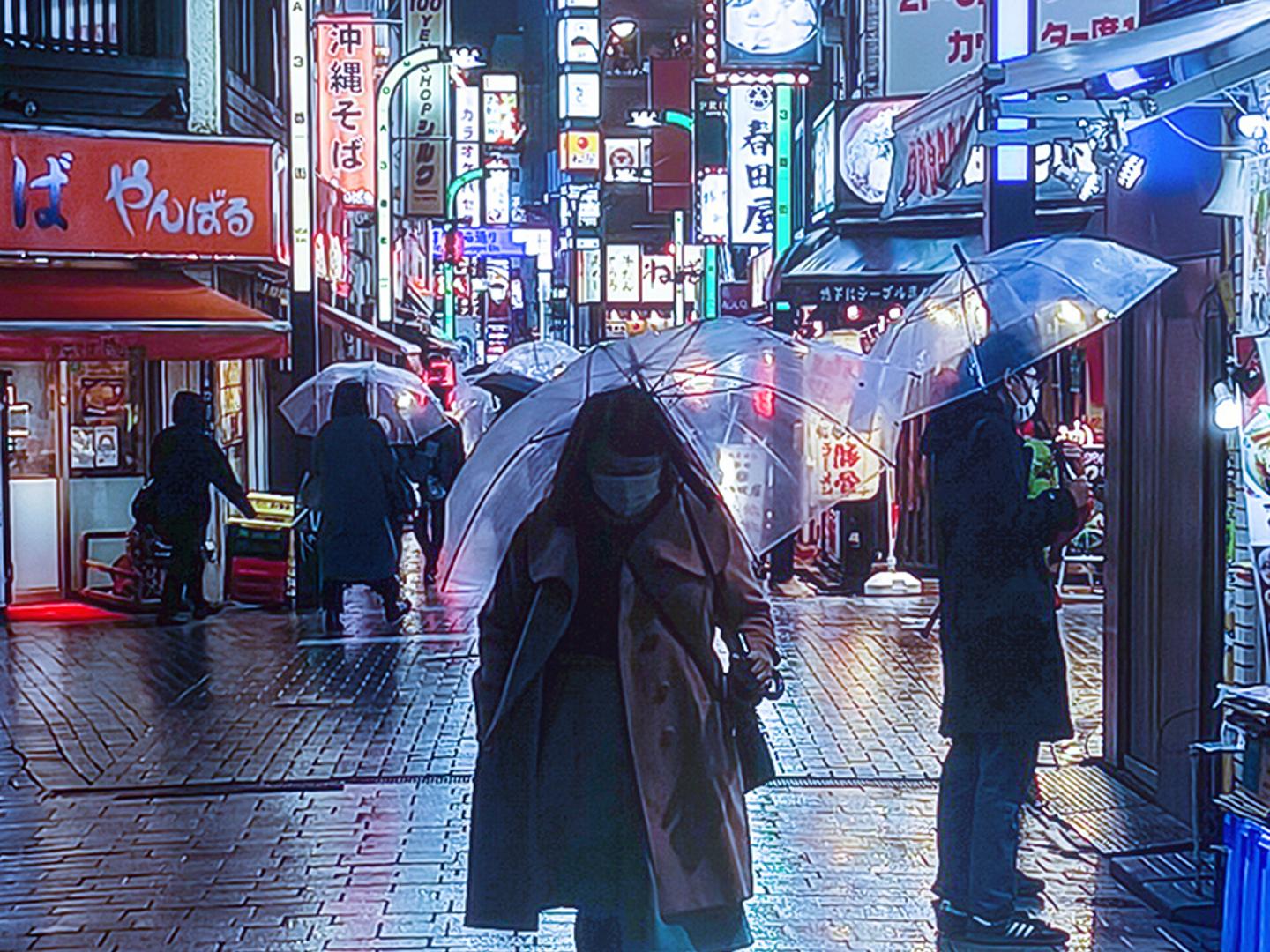 People walk with transparent umbrellas along a brightly lit, rainy street in an urban area at night, with colorful illuminated signs in the background.