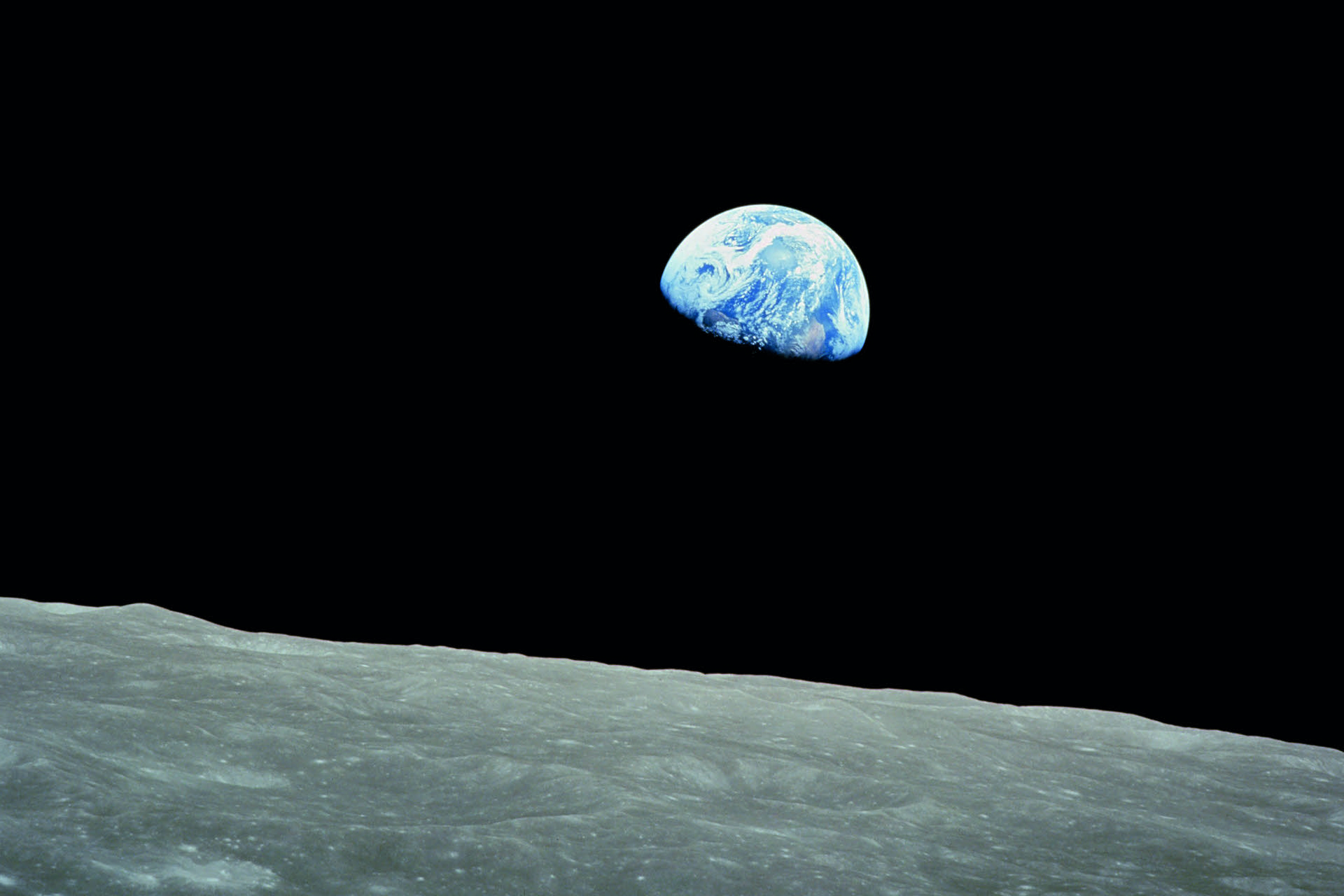 View of Earth rising above the lunar horizon, captured from the surface of the Moon.