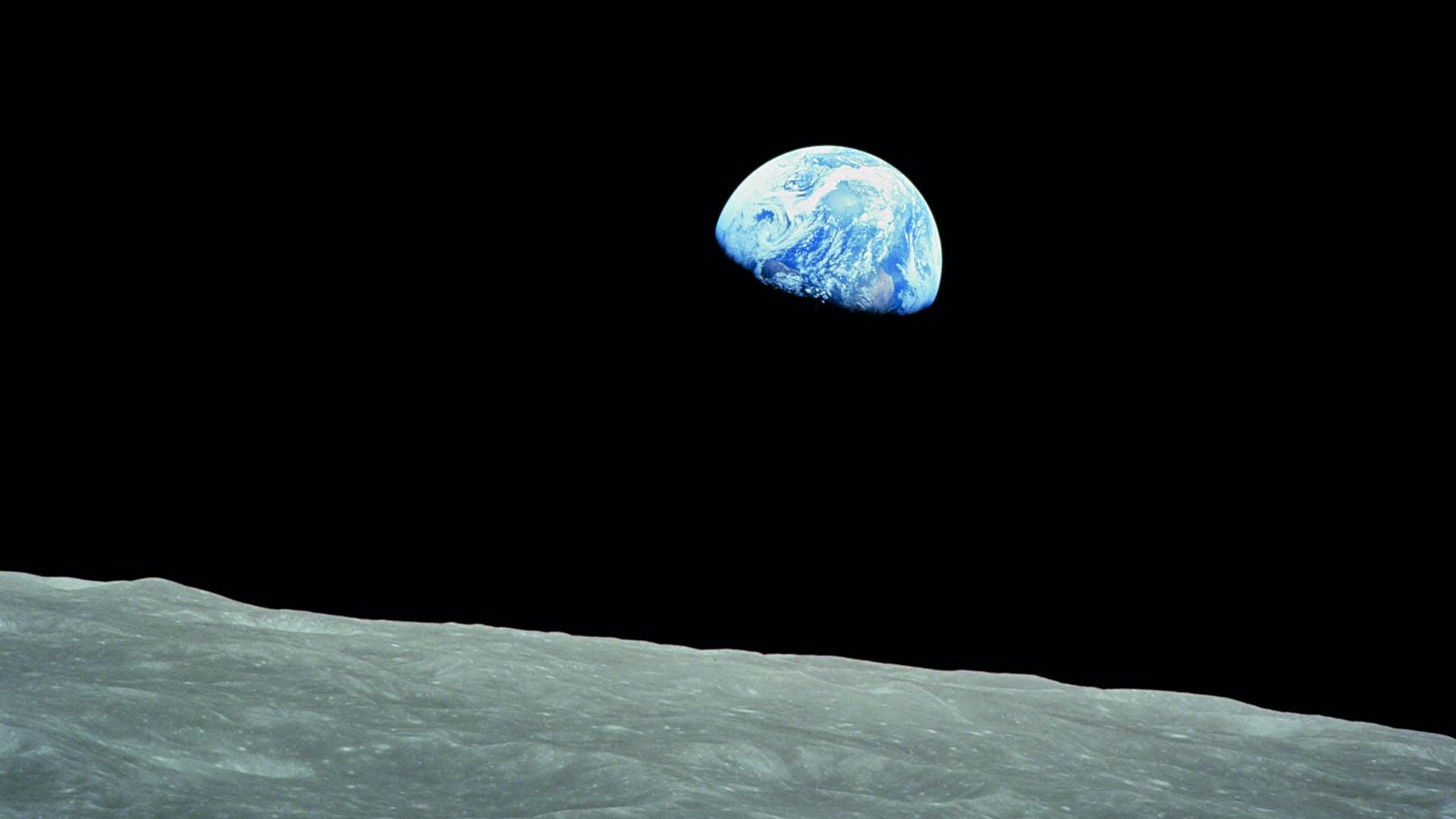 View of Earth rising above the lunar horizon, captured from the surface of the Moon.