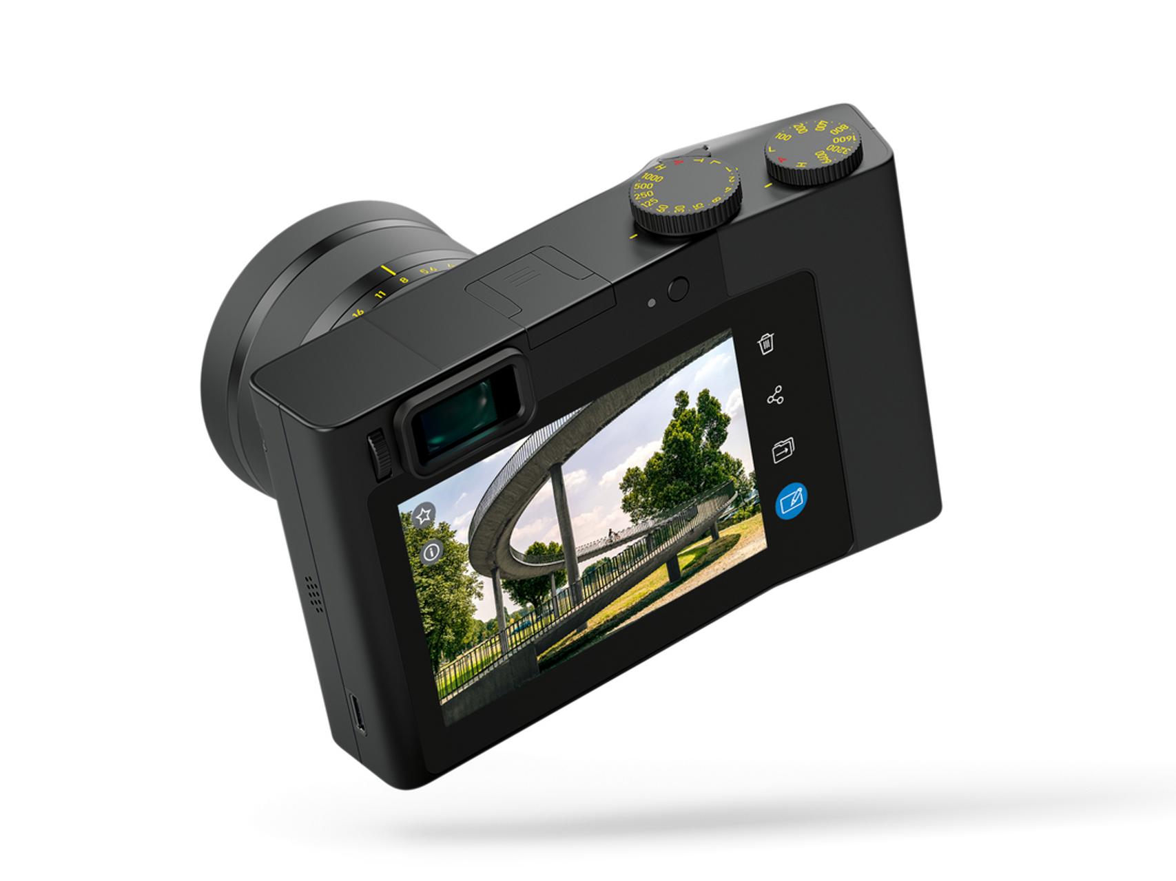 Rear view of a ZEISS digital camera displaying a color image on its screen, with control dials and buttons visible.