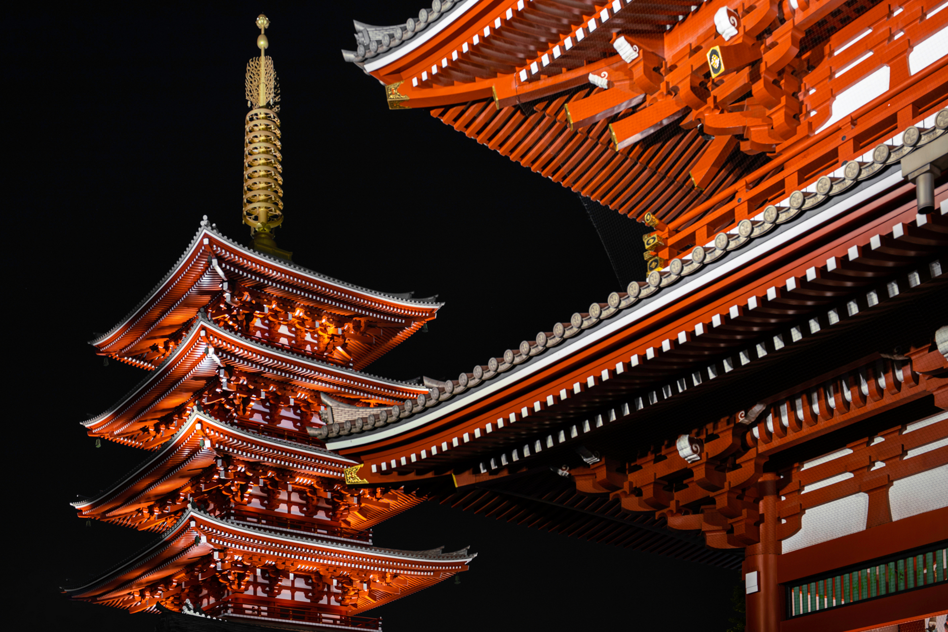 Illuminated traditional Japanese pagoda and temple roof captured in sharp detail at night, showcasing ZEISS optical precision.