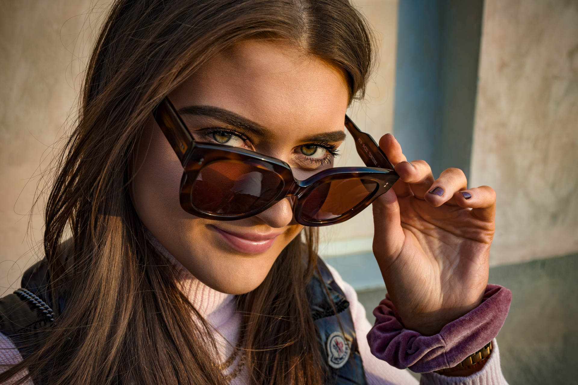 Woman smiling and looking into the camera while adjusting her sunglasses with ZEISS lenses.