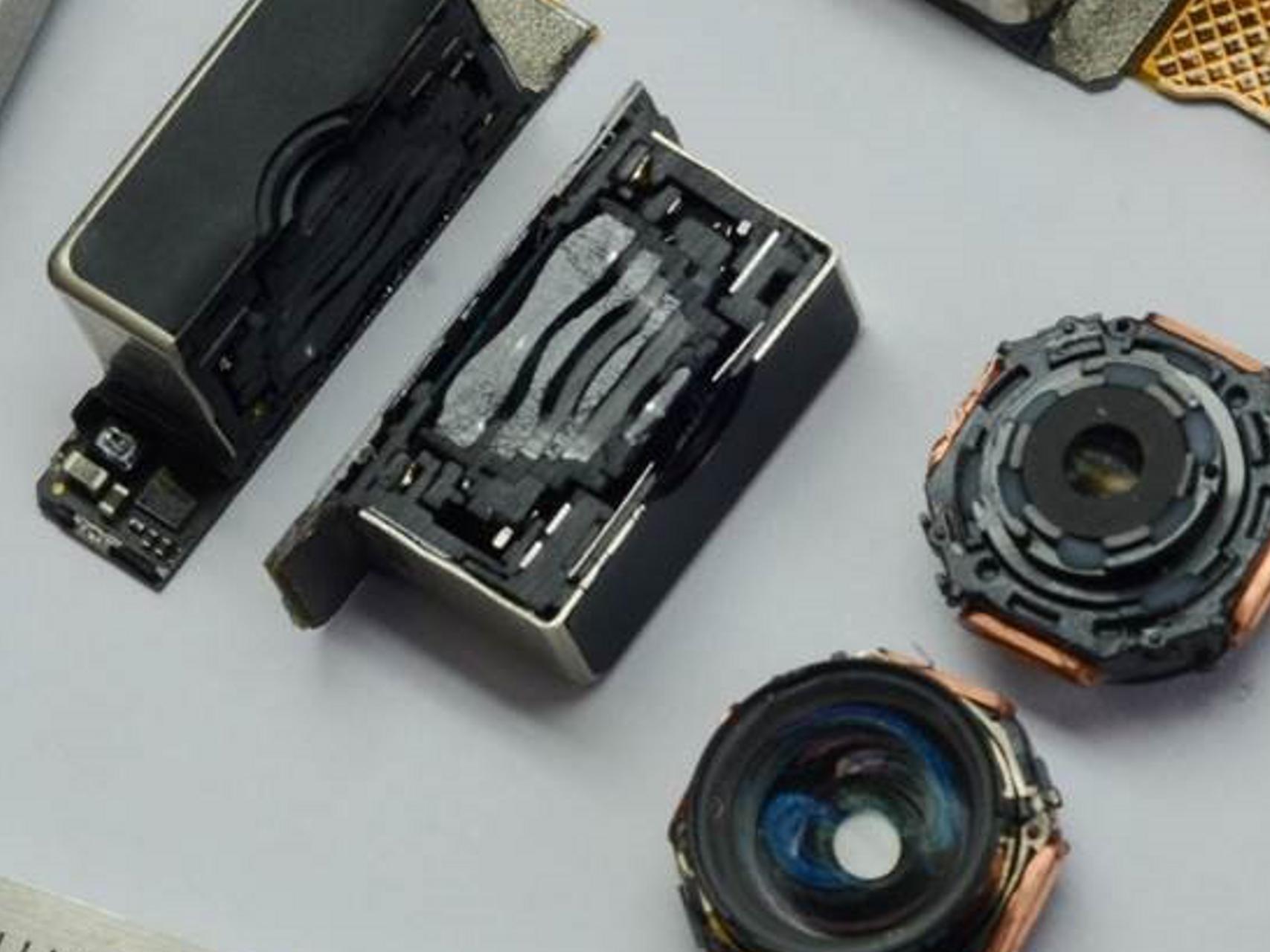 Close-up view of disassembled ZEISS camera lens components and optical modules arranged on a light surface.