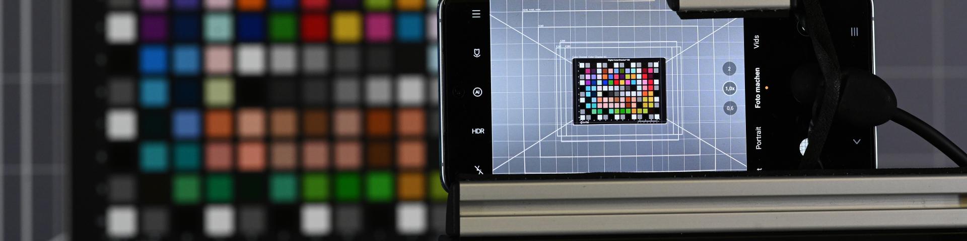 A smartphone mounted on a testing rig captures an image of a color calibration chart in a controlled ZEISS lab environment.