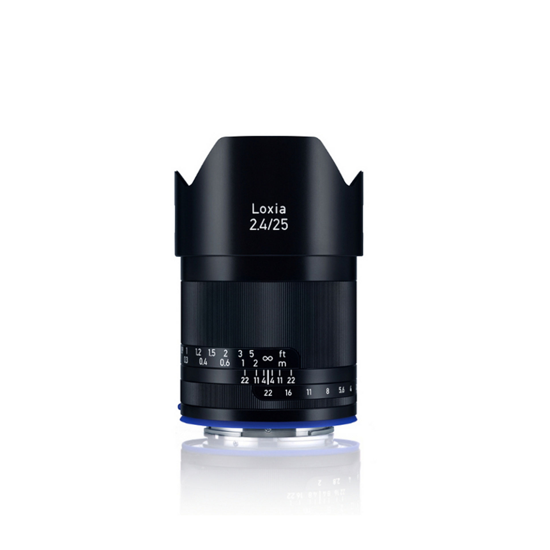 Black ZEISS Loxia 2.4/25 camera lens standing upright on a white reflective surface.