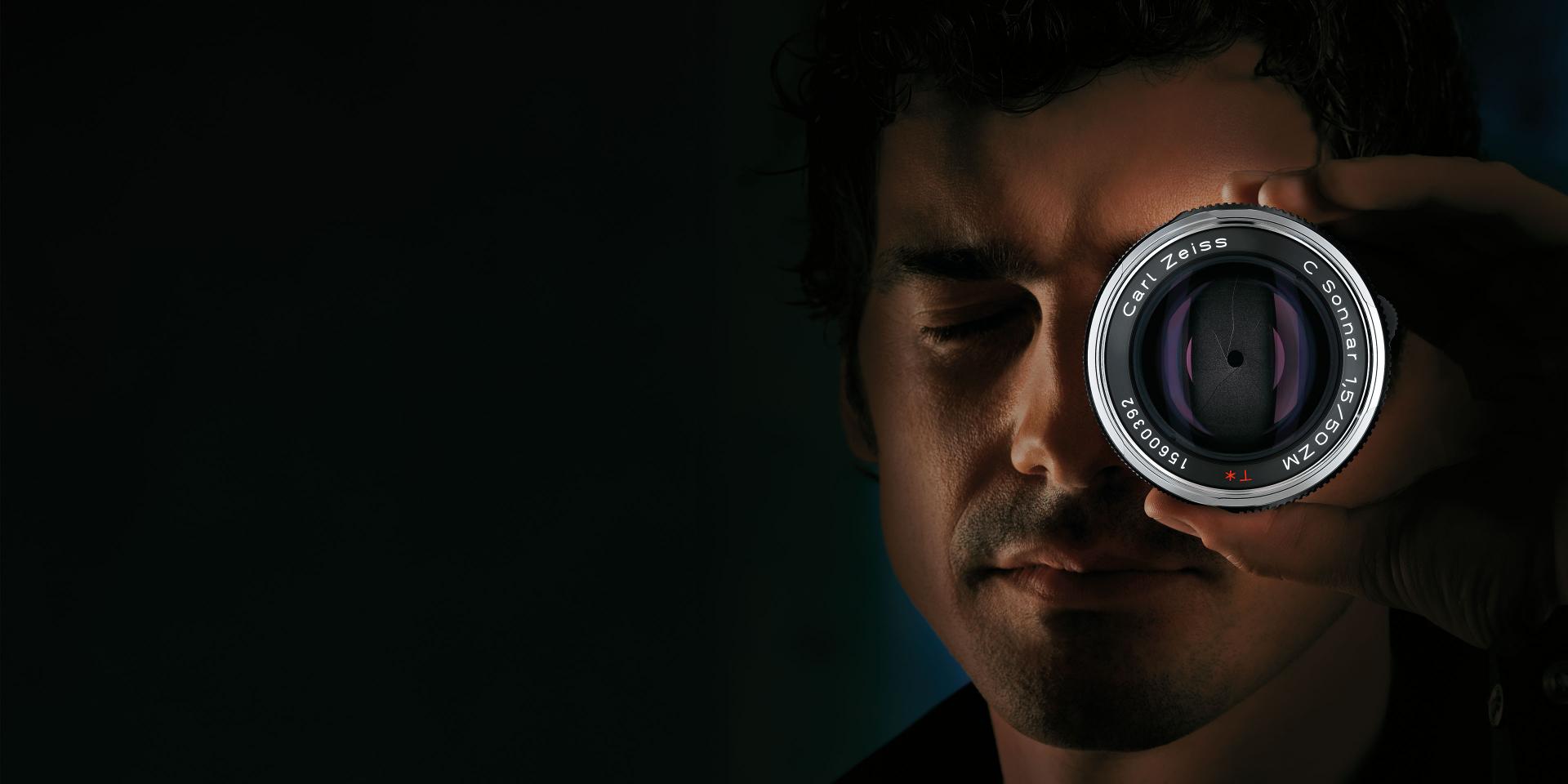 Close-up view of a ZEISS camera lens with visible aperture blades and engraved serial number.