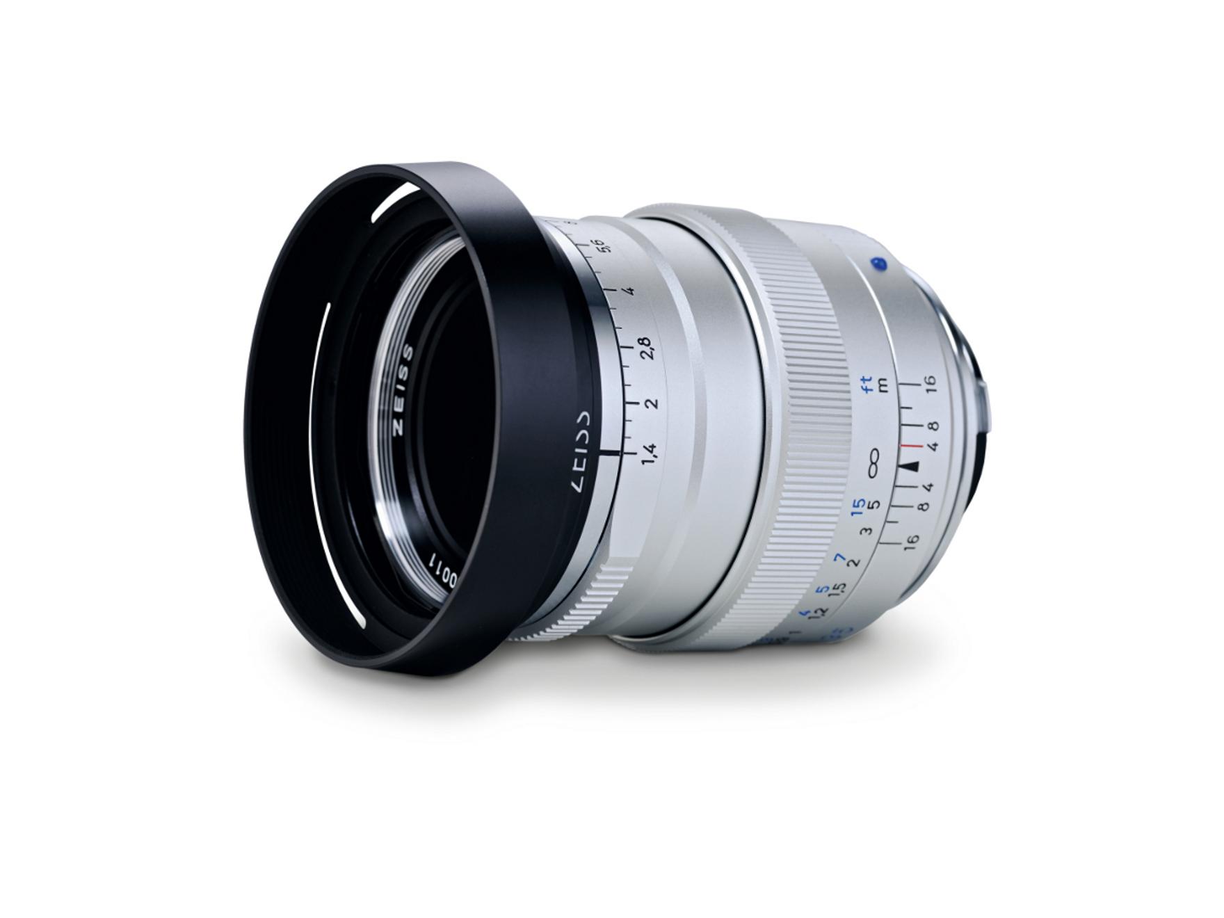 Silver ZEISS camera lens with black lens hood, featuring detailed focus and aperture markings on a white background.