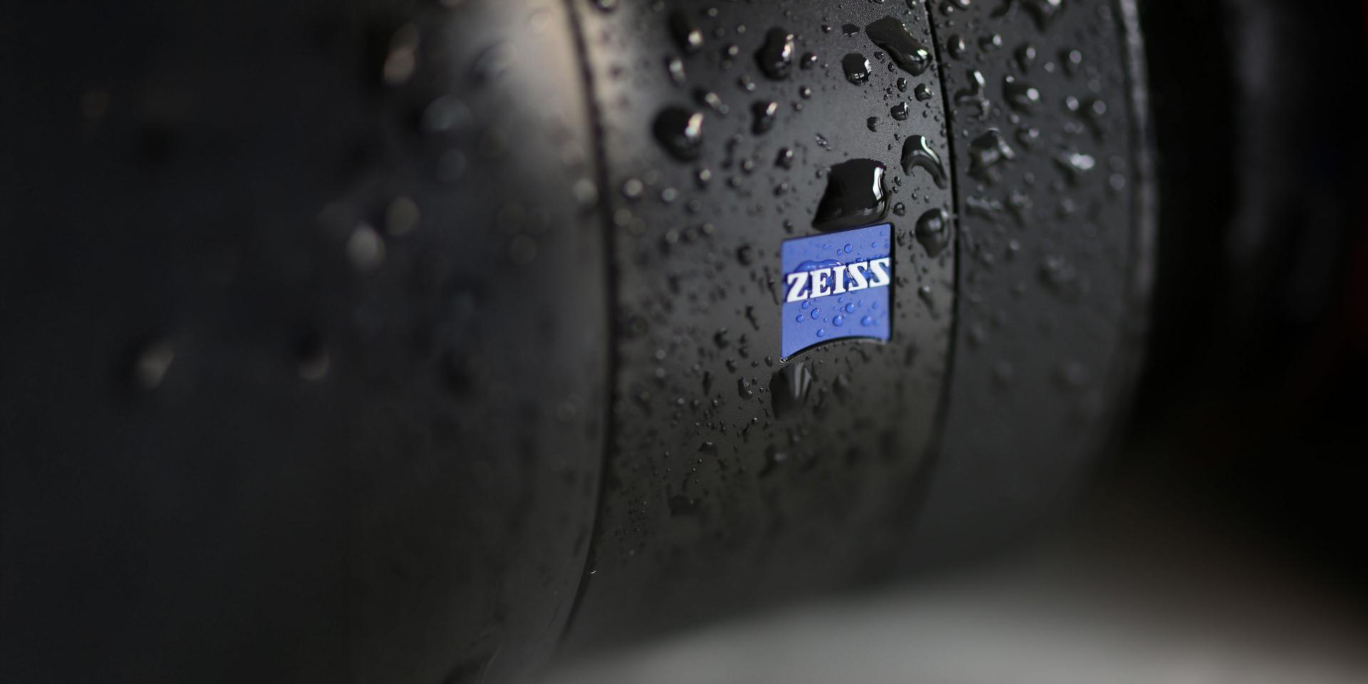 Close-up of a ZEISS lens with water droplets on its surface.