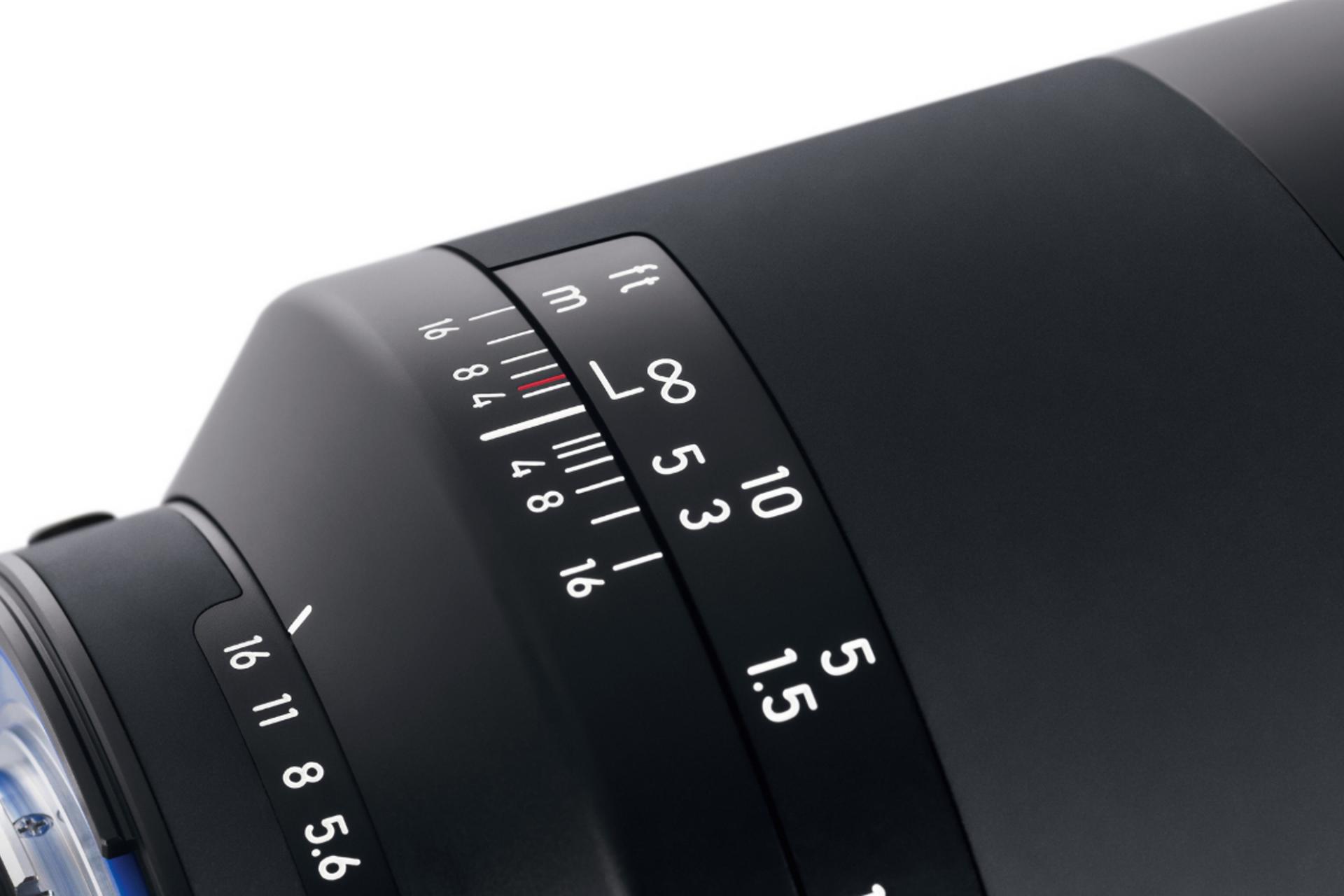Close-up view of a ZEISS camera lens showing focus and aperture distance markings in feet and meters.