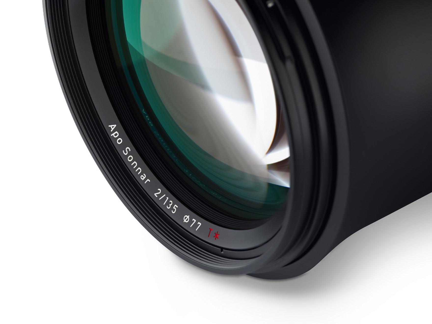 Close-up view of a ZEISS Apo Sonnar 2/135 camera lens showing detailed glass elements and engraved product labeling.