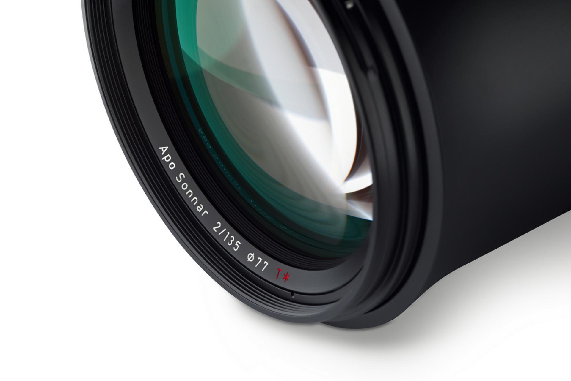 Close-up view of a ZEISS Apo Sonnar 2/135 camera lens showing detailed glass elements and engraved product labeling.